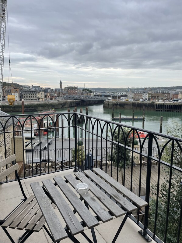 A riverside view with a wooden deck and metal railing, overlooking a town with buildings and a bridge. - La Tour Aux Crabes (Dieppe)