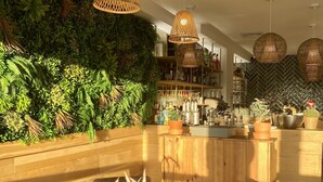 A cozy bar area with wooden furniture, a green wall with plants, and hanging wicker lamps. - La Tour Aux Crabes (Dieppe)