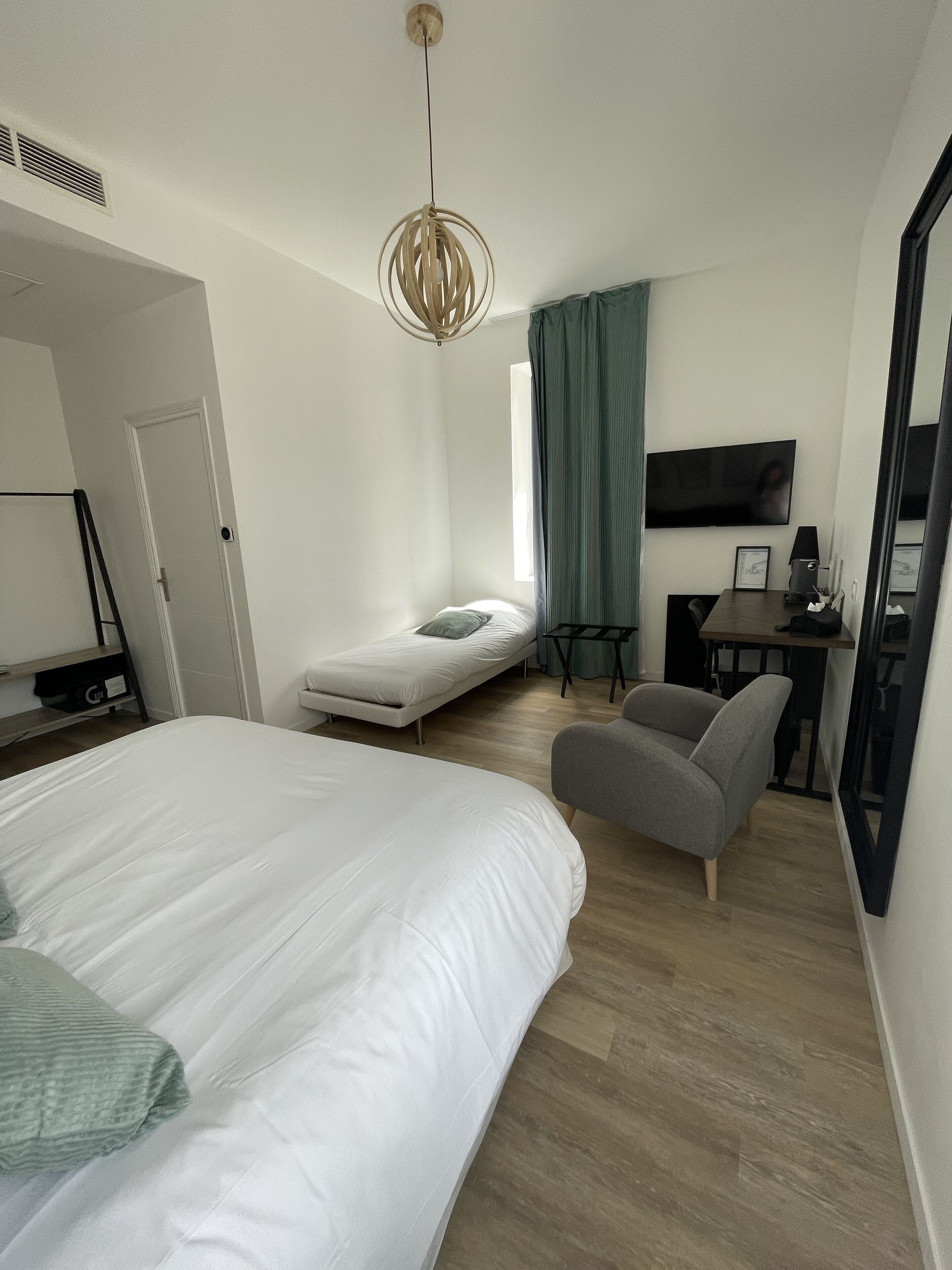 Una habitación de hotel moderna con una cama grande, un escritorio con silla, una televisión y una ventana con cortinas.