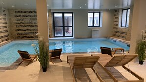 An indoor swimming pool with lounge chairs and potted plants. - La Tour Aux Crabes (Dieppe)