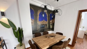 Un comedor con una mesa de madera, seis sillas, un amplio muro decorativo y una planta en maceta.