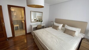 Un dormitorio con una cama grande, un escritorio, una silla, un espejo y una lámpara colgante.