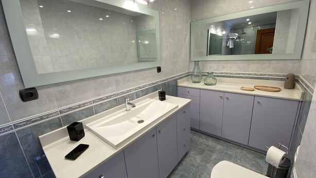 Ein modernes Badezimmer mit großem Spiegel, doppelter Waschbecken und Toilette.