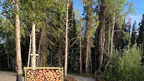 Ein Picknicktisch mit Feuerstelle, umgeben von Kies und einem Holzstapel.