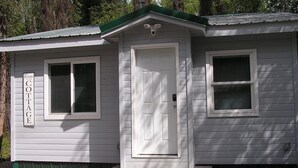 Ein kleines, eingeschossiges Cottage mit einer weißen Tür und zwei Fenstern, jeweils mit Fensterläden.