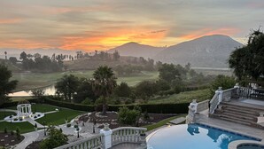 A pool area with a view of a golf course and mountains.