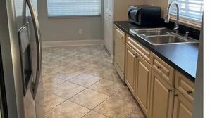 A compact kitchen with a refrigerator, microwave, sink, and beige cabinets. - Tampa home (Tampa)