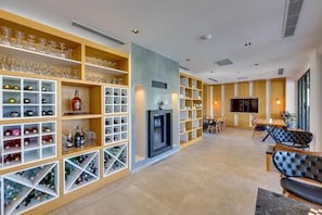 Un interior moderno con chimenea, estantes llenos de copas y botellas de vino, y un área de comedor con sillas y una mesa.