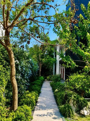 A pathway flanked by lush greenery and a building with a white facade and red accents. - Celeste Bella Luxury Hotel & Spa (Bodrum)