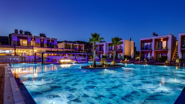 Una piscina con zona de bar, palmeras y edificios modernos.