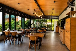 A restaurant with wooden tables and chairs, large windows, and a ceiling fan. - Celeste Bella Luxury Hotel & Spa (Bodrum)