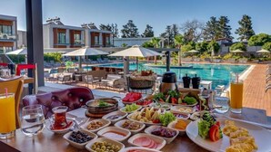 Un bufé de desayuno con vistas a la piscina, que incluye diversos alimentos y bebidas.