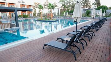 Una piscina al aire libre de temporada, sombrillas