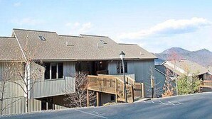 Un bâtiment à deux étages doté d’un espace extérieur couvert et offrant une vue sur les montagnes en arrière-plan.