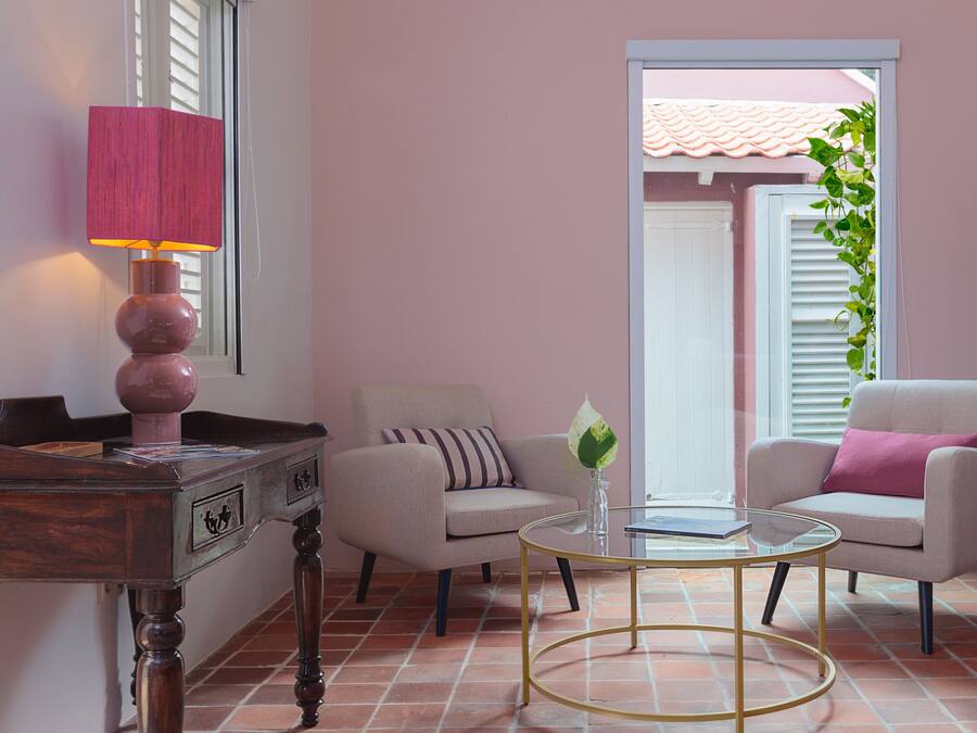 Een kamer met een houten bureau, twee fauteuils, een glazen salontafel en een lamp.
