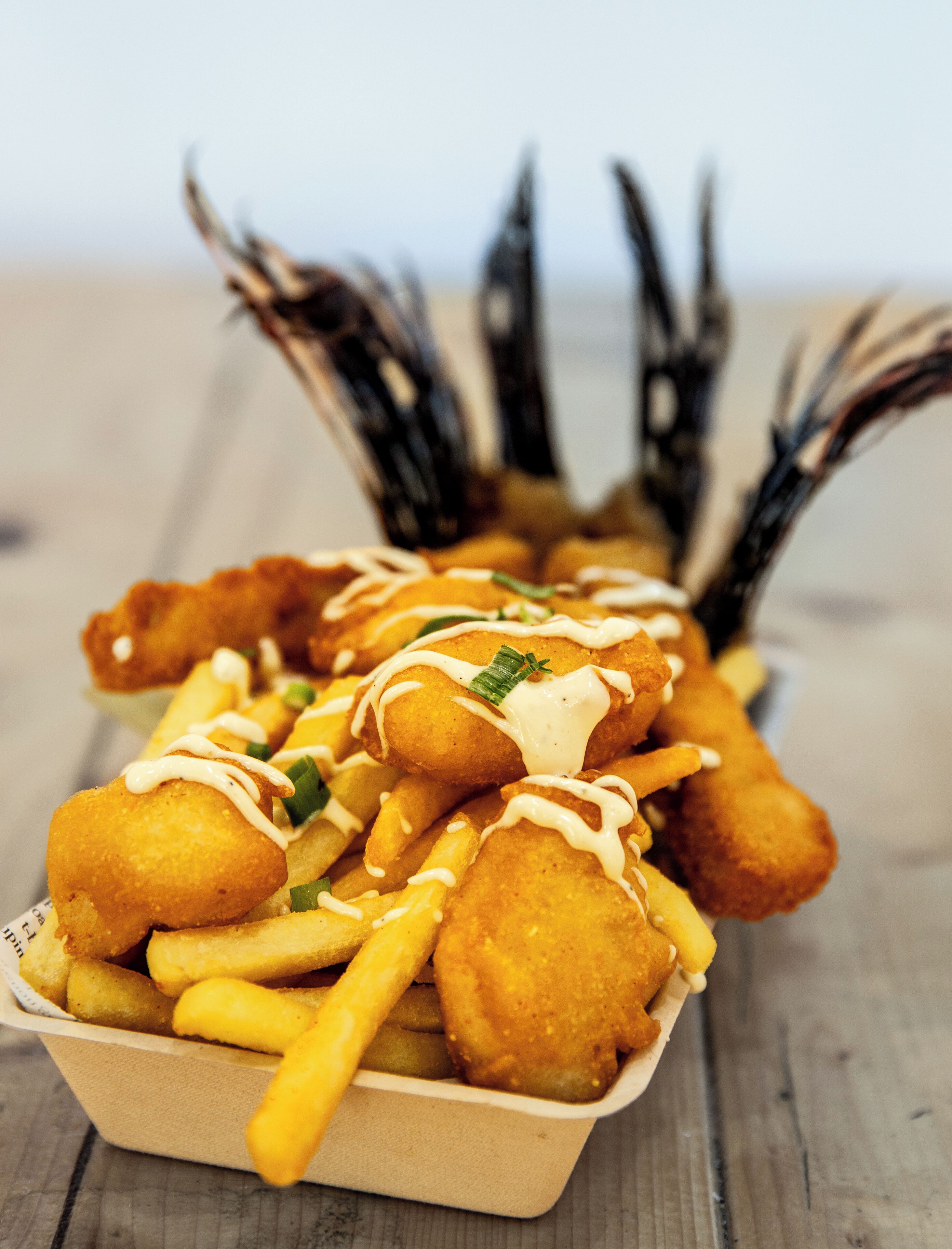 A tray of food including breaded items and fries, served in a paper container.