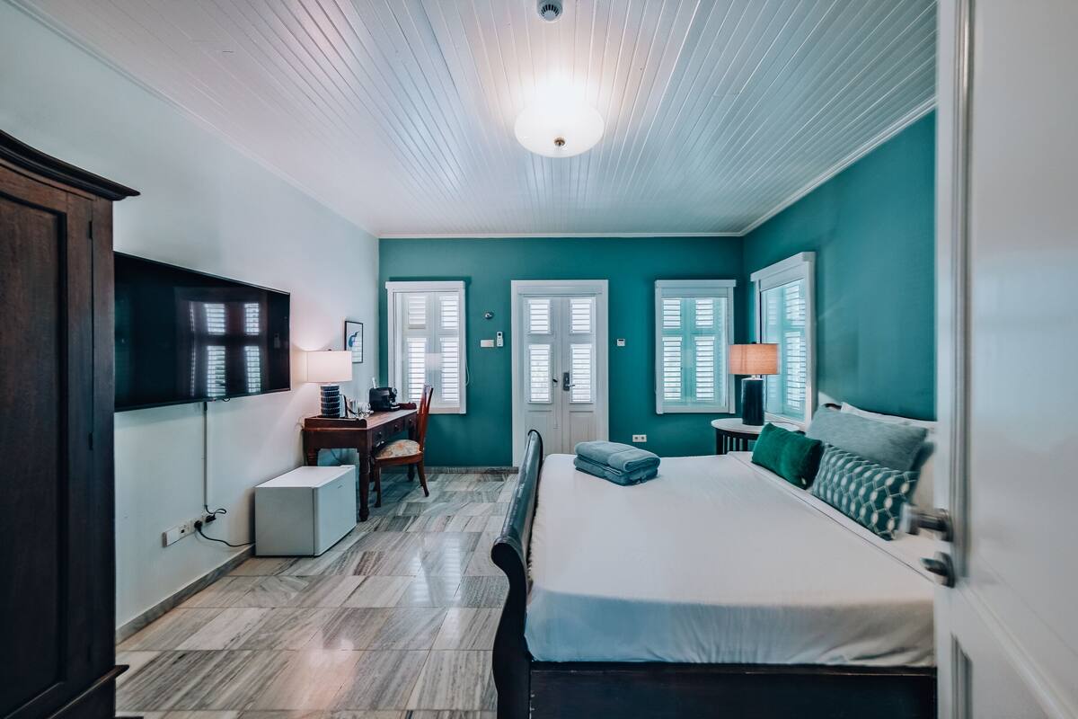 A bedroom with a bed, a desk, a chair, and a television.