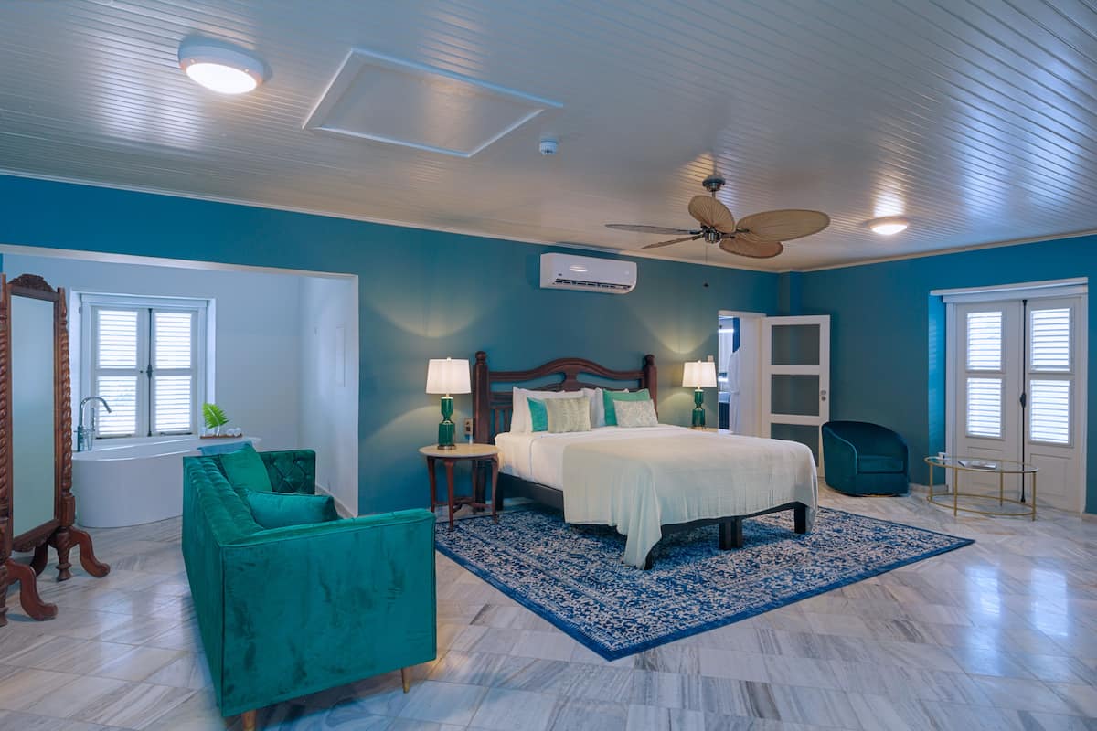 A bedroom with a bed, a chair, a vanity, and a ceiling fan.