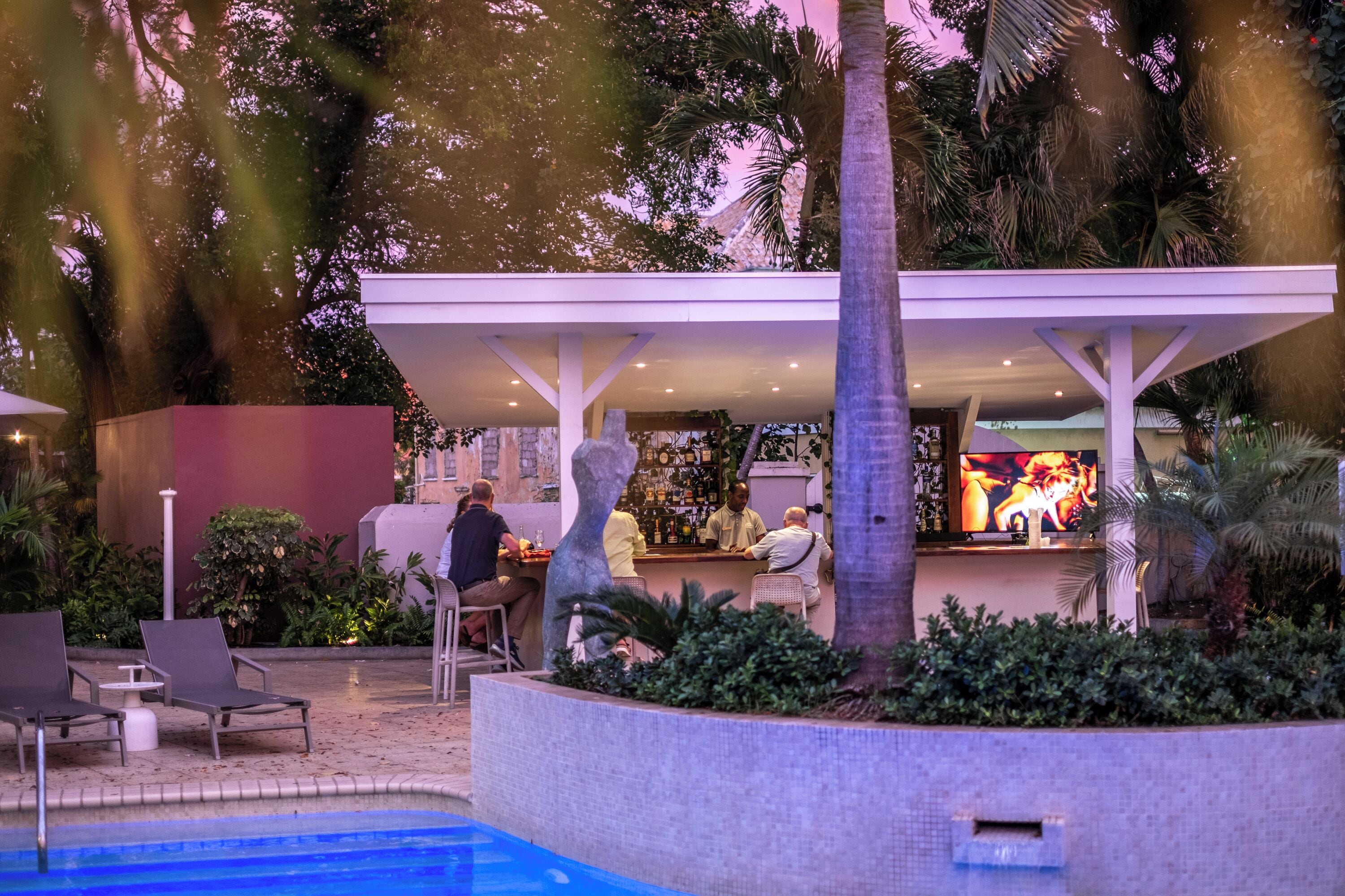 A poolside area with lounge chairs, a bar, and a covered seating area.