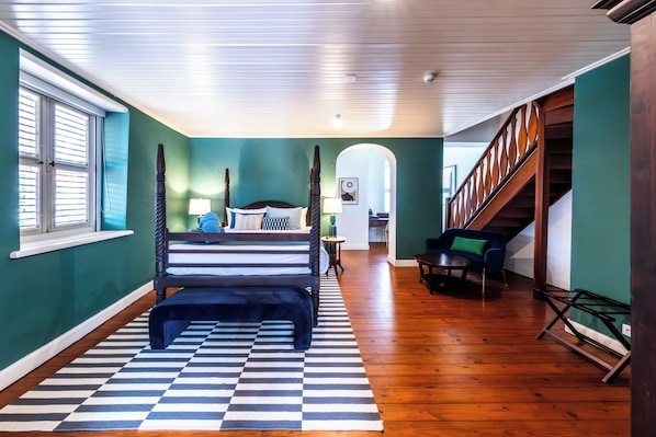 Une chambre à coucher avec un lit, un tapis à carreaux, un escalier et une vue sur un couloir.