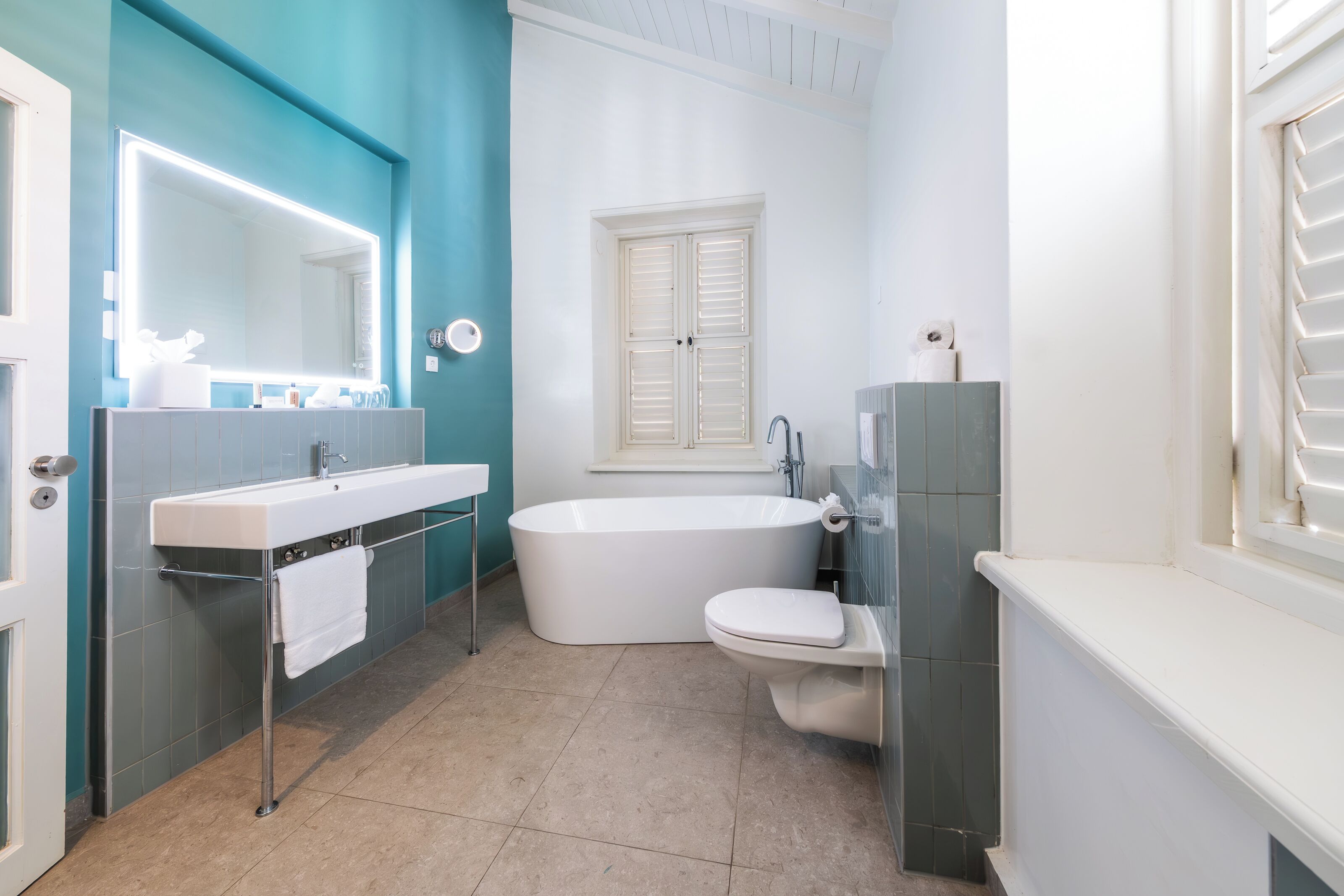 Ein modernes Badezimmer mit großem Spiegel, zwei Waschbecken, einer Badewanne und einer Toilette.