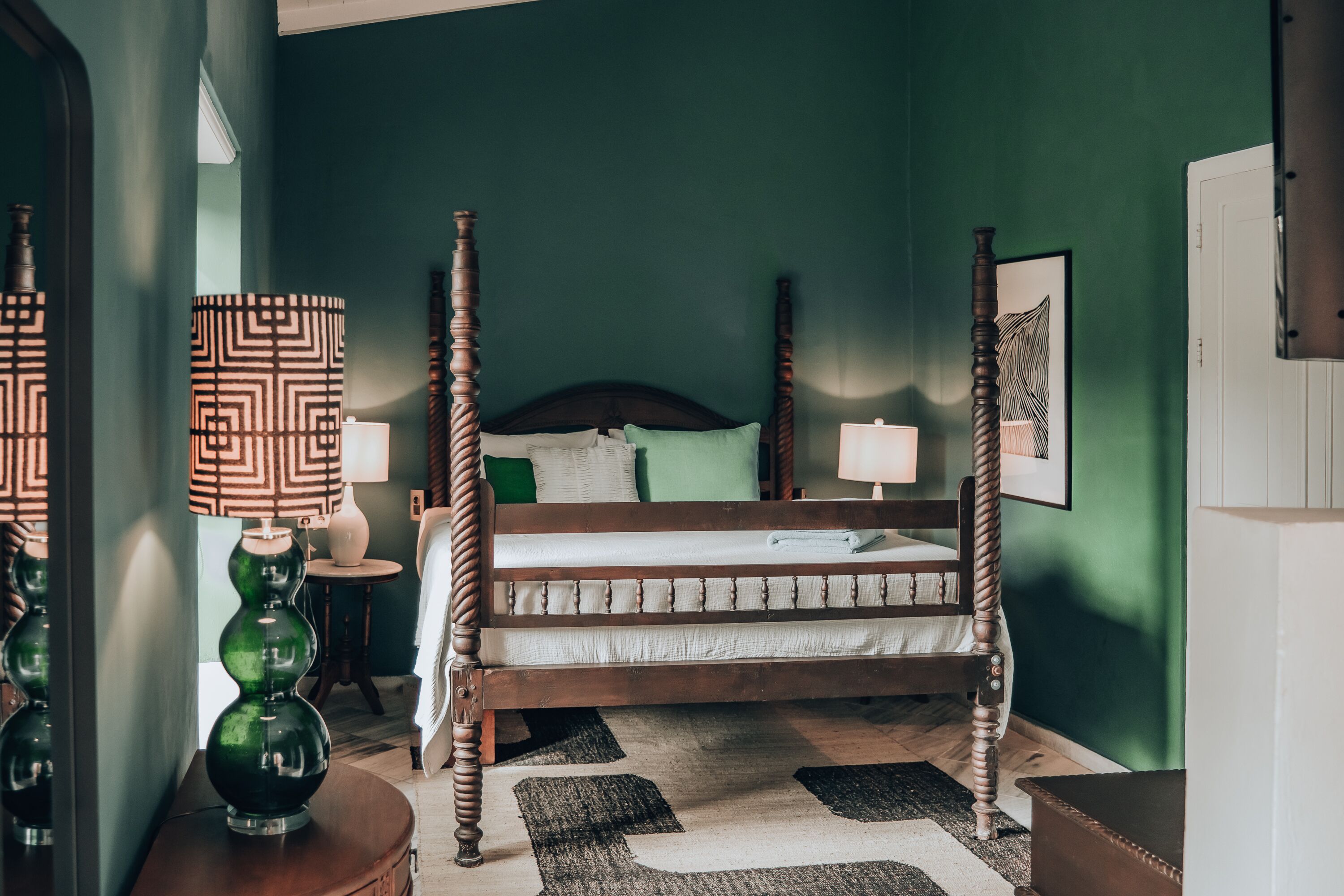 A four-poster bed with a wooden frame and a green wall in the background.