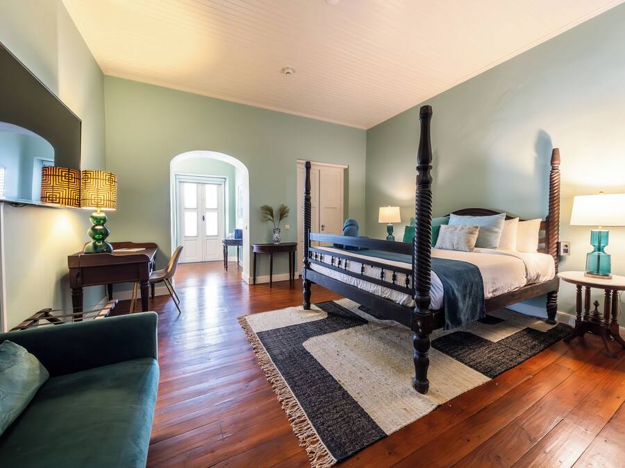 Une chambre à coucher avec un lit à baldaquin, un bureau, une chaise et un canapé.