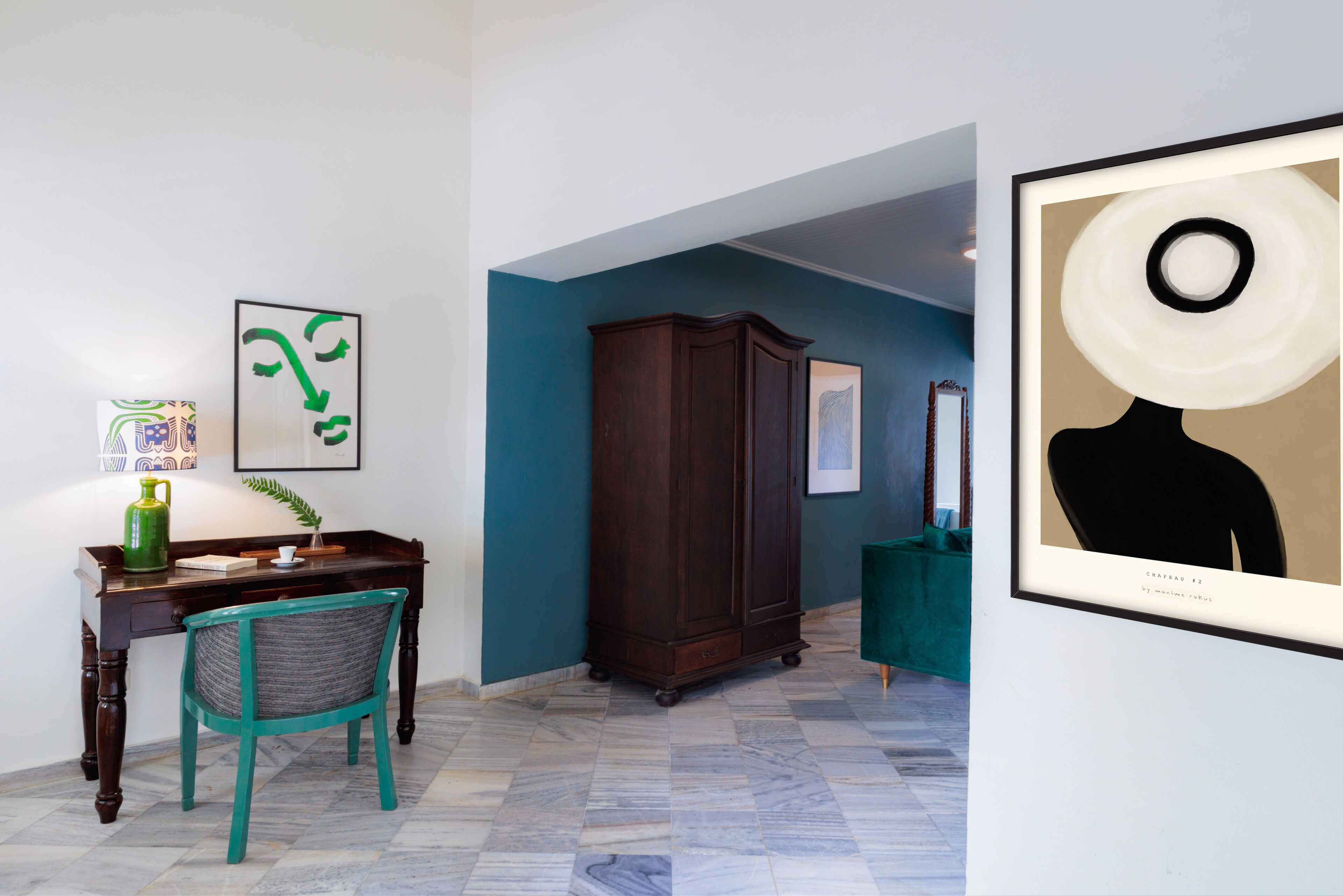 A room with a desk, chair, and artwork on the walls.
