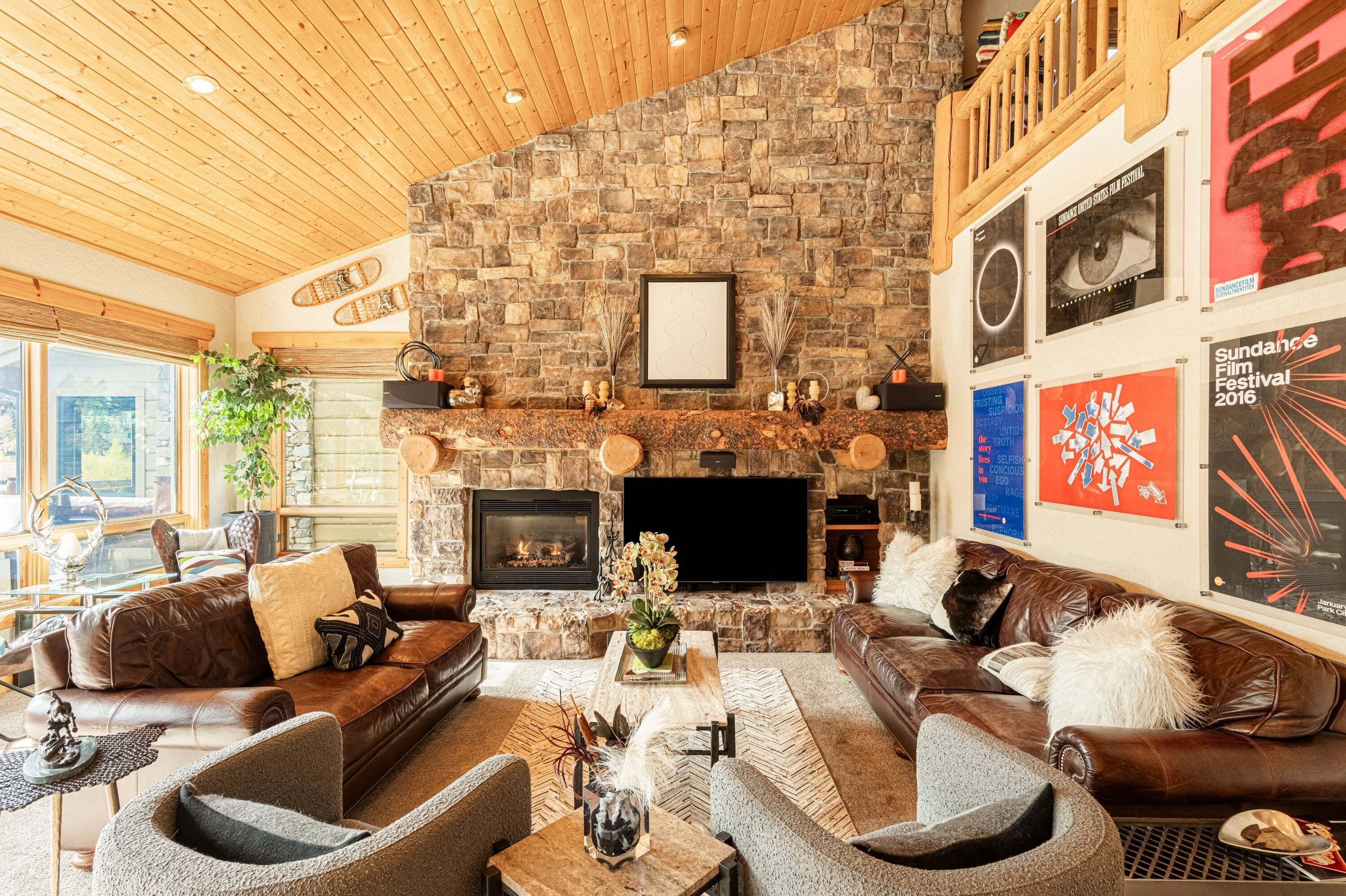 A cozy living room with a stone fireplace, leather sofas, and a flat-screen TV.