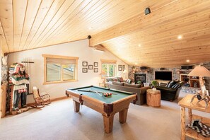 Una habitación acogedora con mesa de billar, sofá, chimenea y televisor.