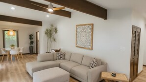 Uma sala de estar moderna com um sofá seccional, uma mesinha e um ventilador de teto.
