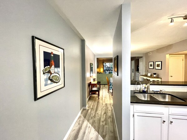A modern kitchen with white cabinets, a stainless steel sink, and a wooden floor. - First floor 2br 2ba, balcony, pool, grill, pavilion, 1 block from Rehoboth Ave (Rehoboth Beach)