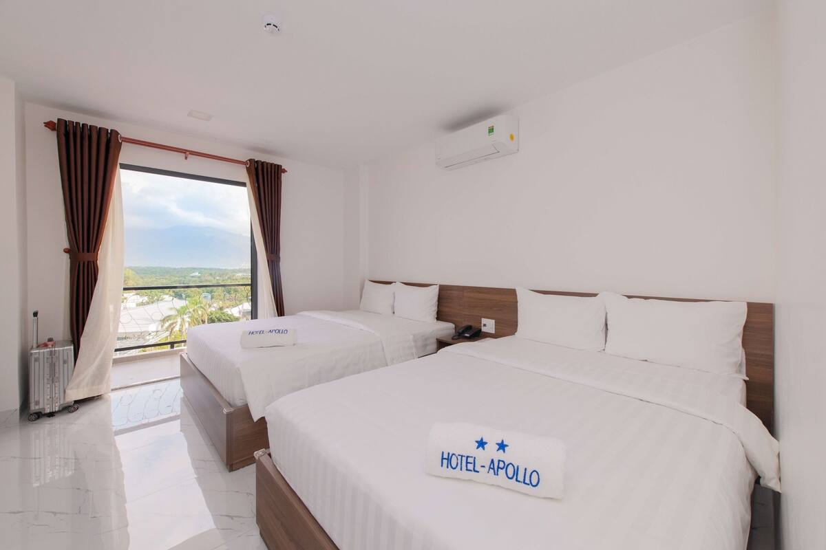 Quarto de hotel com duas camas, vista para o exterior e varanda.