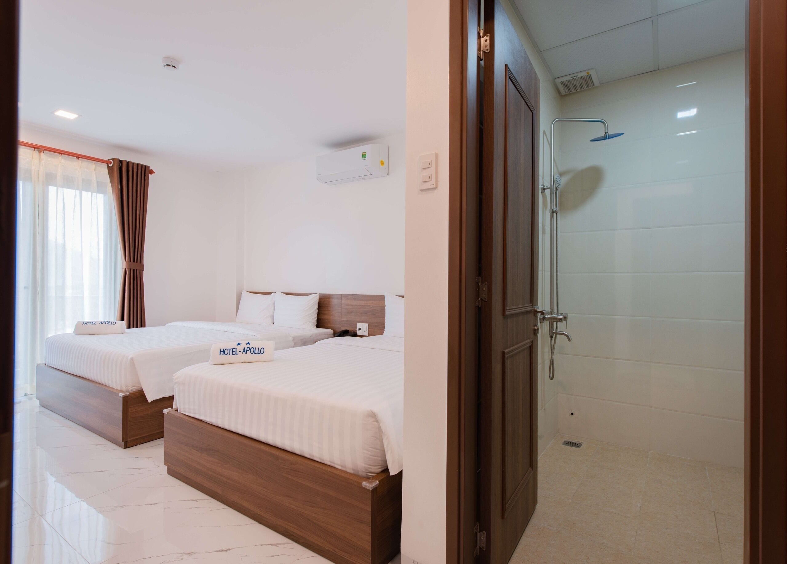 Camera d'albergo con due letti, una doccia e un cartello che indica il nome dell'hotel.