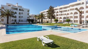 A pool area with multiple swimming pools, a grassy lawn, and white buildings with balconies. - The Algarvean Oasis with Pool by LovelyStay (Alporchinhos)