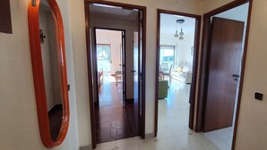 A hallway with a wooden door, a mirror, and a view into a living area with a sofa and a dining table. - The Algarvean Oasis with Pool by LovelyStay (Alporchinhos)
