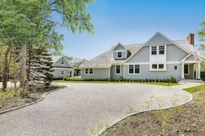 A two-story house with a grey exterior, a driveway, and a well-maintained lawn.