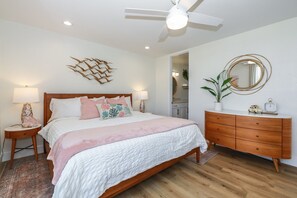 A bedroom with a bed, bedside tables, a dresser, a ceiling fan, and a mirror.