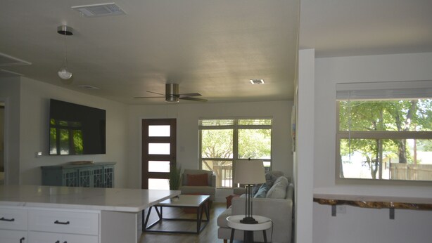A modern living room with a sofa, coffee table, and lamp. There is a kitchen area with cabinets and a countertop.