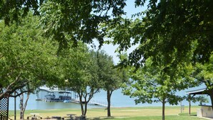 A park with picnic tables, a gazebo, and a view of a lake with boats.