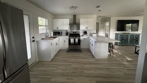 A modern kitchen with white cabinetry, a central island, stainless steel appliances, and a patterned backsplash.