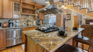 A kitchen with wooden cabinets, stainless steel appliances, and a granite countertop. - Downtown House w/Parking! On Spring St, Hot Tub! (Eureka Springs)