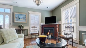 A living room with a fireplace, a television, and a sofa. - Downtown House w/Parking! On Spring St, Hot Tub! (Eureka Springs)