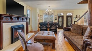A living room with a fireplace, leather armchairs, a sofa, and a television. - Downtown House w/Parking! On Spring St, Hot Tub! (Eureka Springs)