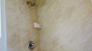 Een badkamer met douche, toilet en bad.