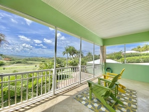 Un balcon donnant sur un paysage verdoyant et des palmiers.