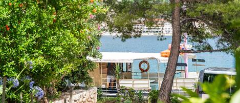 A boat docked near a body of water, surrounded by greenery and a stone wall.