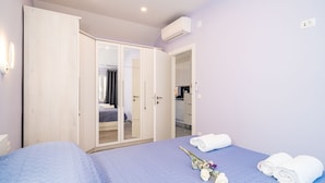 Ein Schlafzimmer mit Bett, Kleiderschrank und einem durchgegangenen Tür einsehbaren Badezimmer.