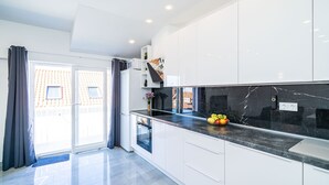 Eine moderne Küche mit weißen Schränken, einer schwarzen Marmorarbeitsplatte und einem eingebauten Backofen.