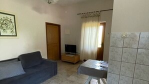 Un salon avec un canapé, une petite table, un téléviseur et une poubelle.